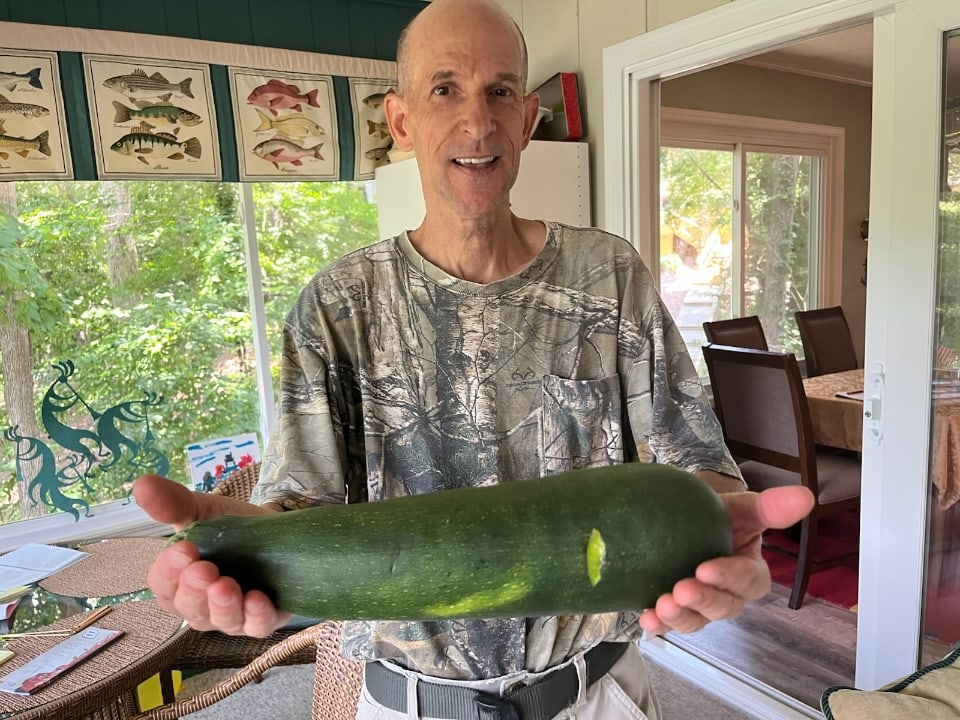 Scott Saunders holding a large homegrown zucchini